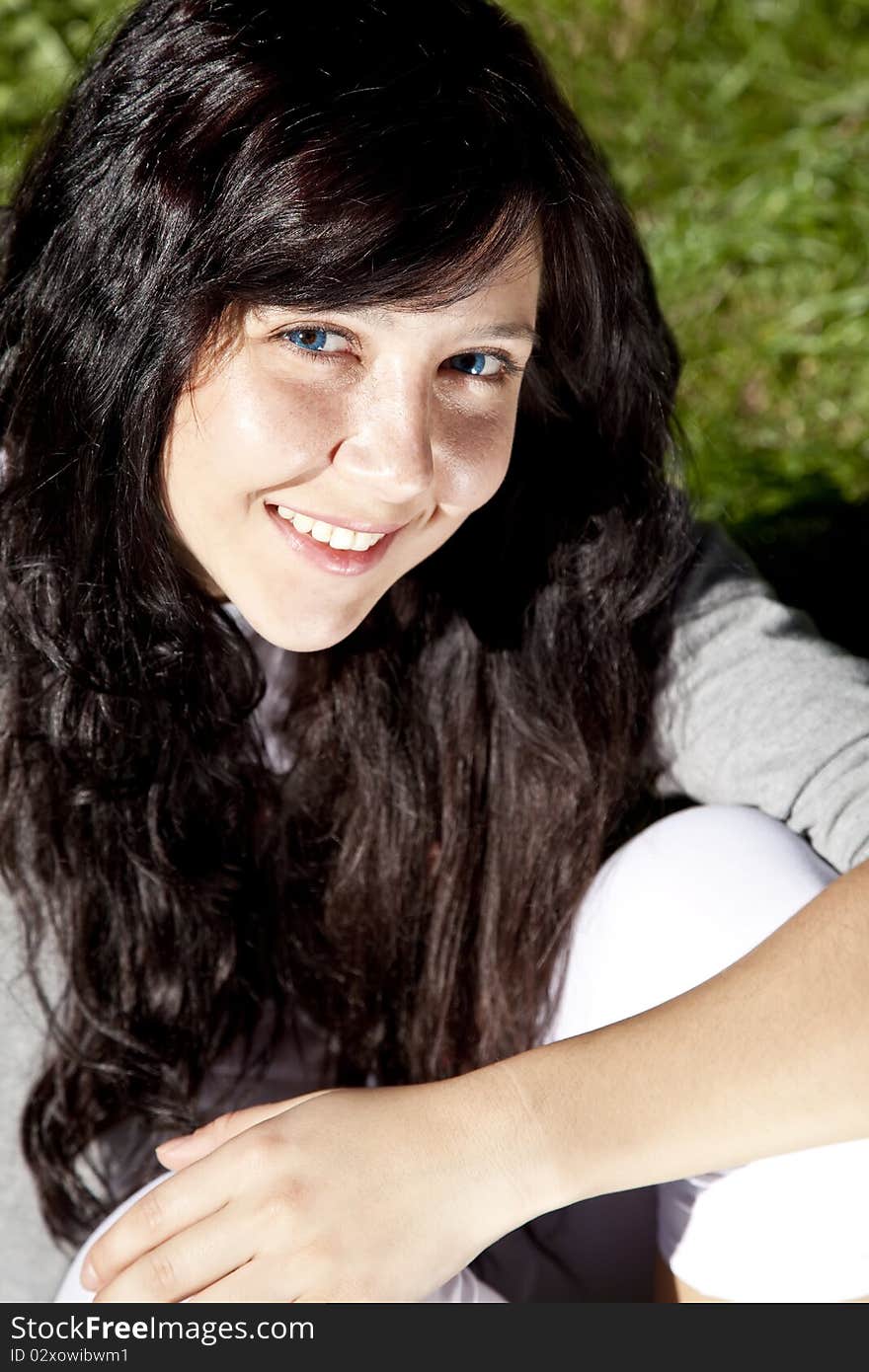 Brunette girl on green grass in the park.