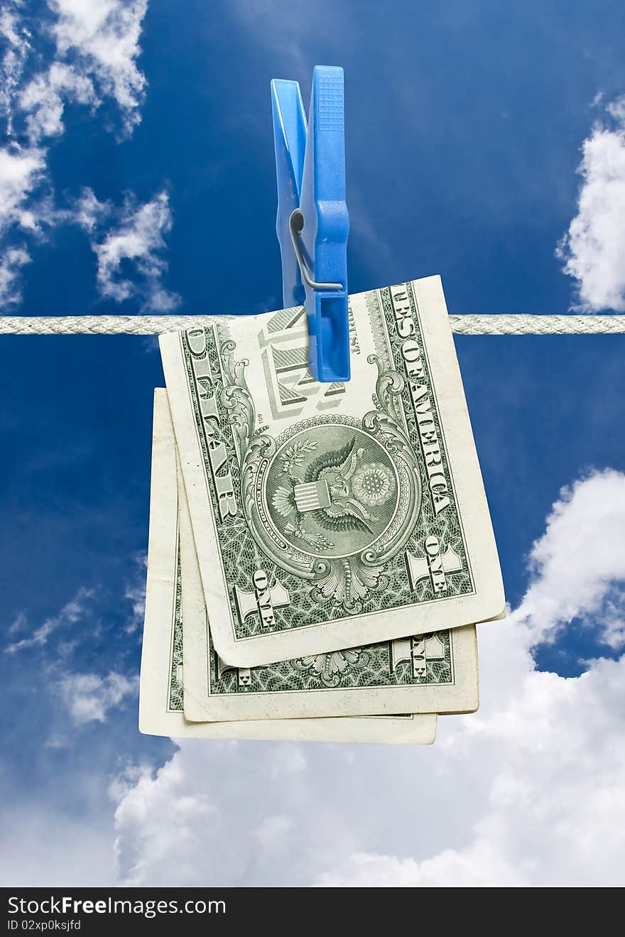 U.s. dollar on rope with clothespin over blue sky. U.s. dollar on rope with clothespin over blue sky