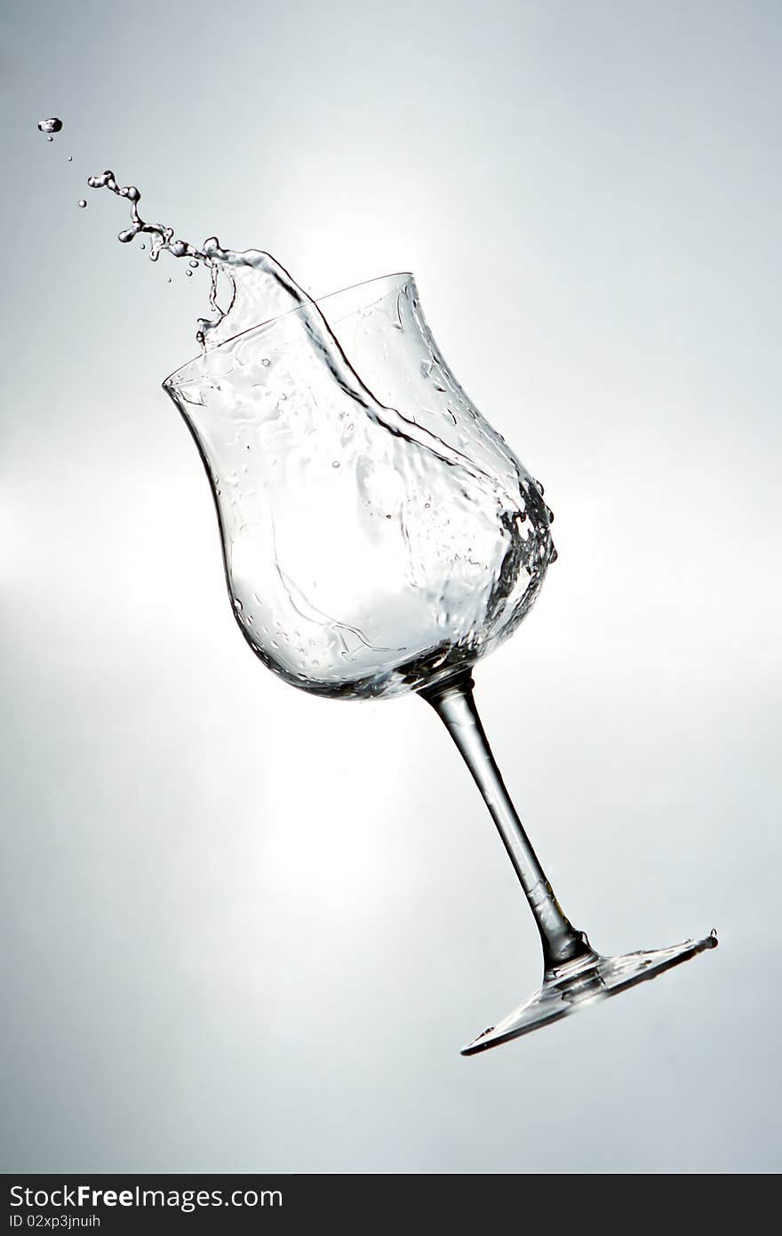 White drink being poured into a wine glass.