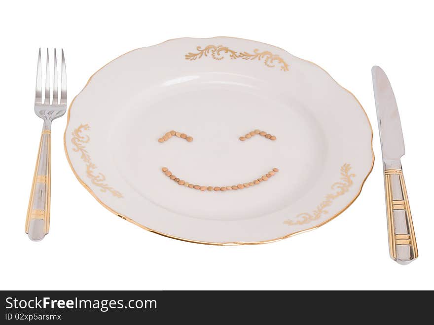 Plate, plug and knife on a white background, with clipping paths. On a plate the smilie from lentil is represented. Plate, plug and knife on a white background, with clipping paths. On a plate the smilie from lentil is represented