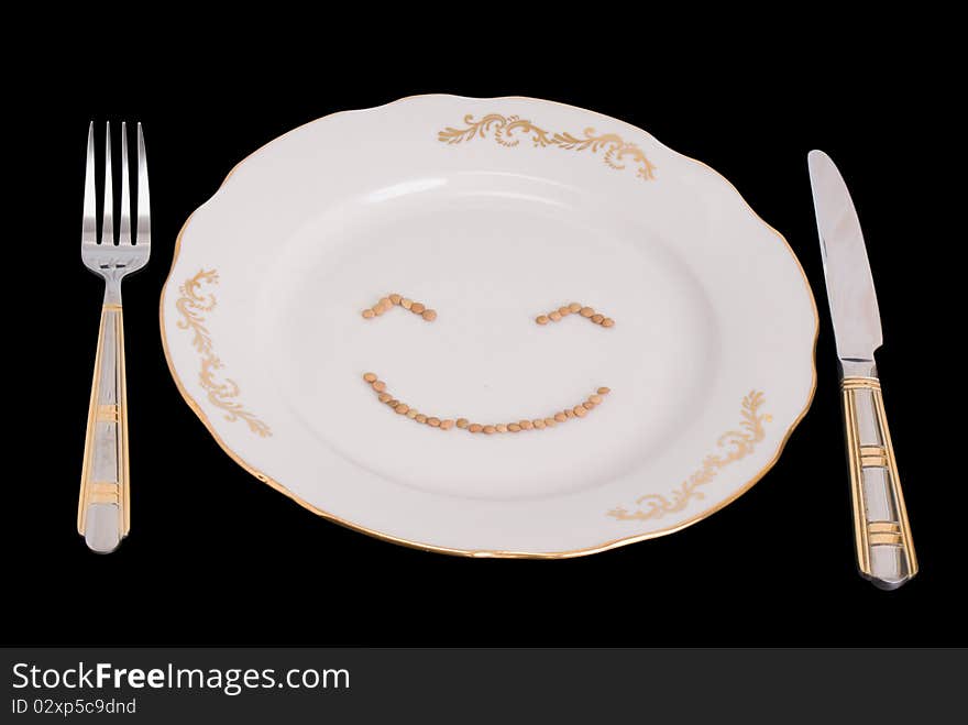 Plate, plug and knife on black background, with clipping paths. On a plate the smilie from lentil is represented. Plate, plug and knife on black background, with clipping paths. On a plate the smilie from lentil is represented