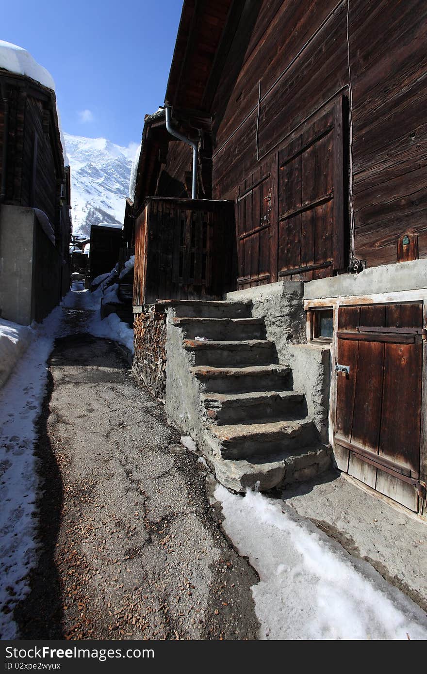 Little path between traditional cottages in Saas-Fee village in the Swiss Alps. The community is considered to be a very attractive winter sport destination . Little path between traditional cottages in Saas-Fee village in the Swiss Alps. The community is considered to be a very attractive winter sport destination .