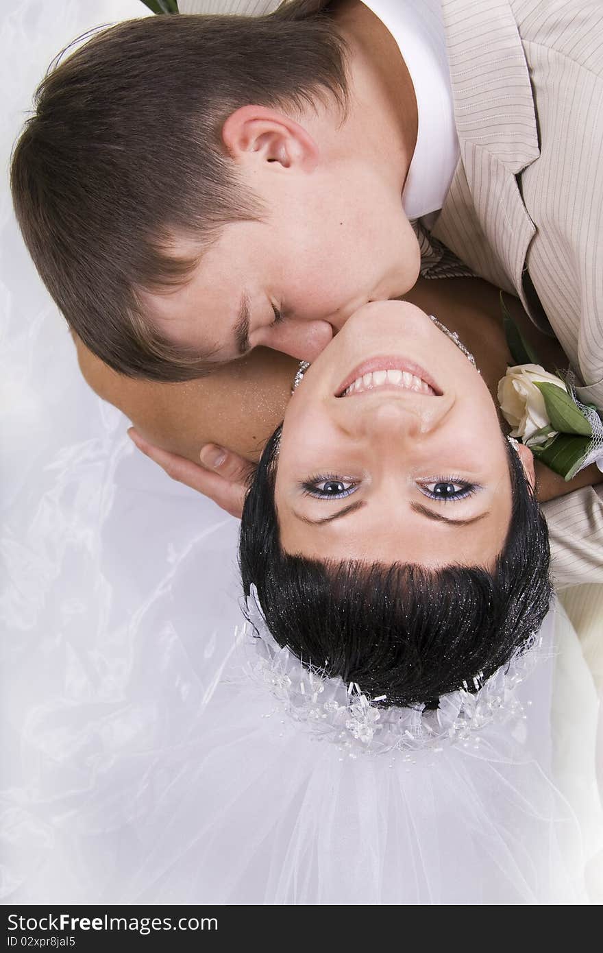 Loving groom and beautiful bride are happy together. A white background.