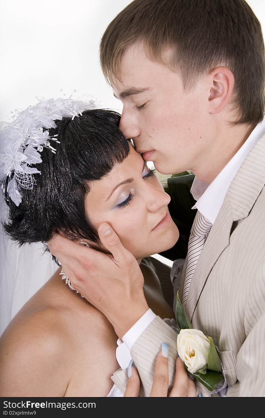 Loving groom and beautiful bride are happy together. A white background.