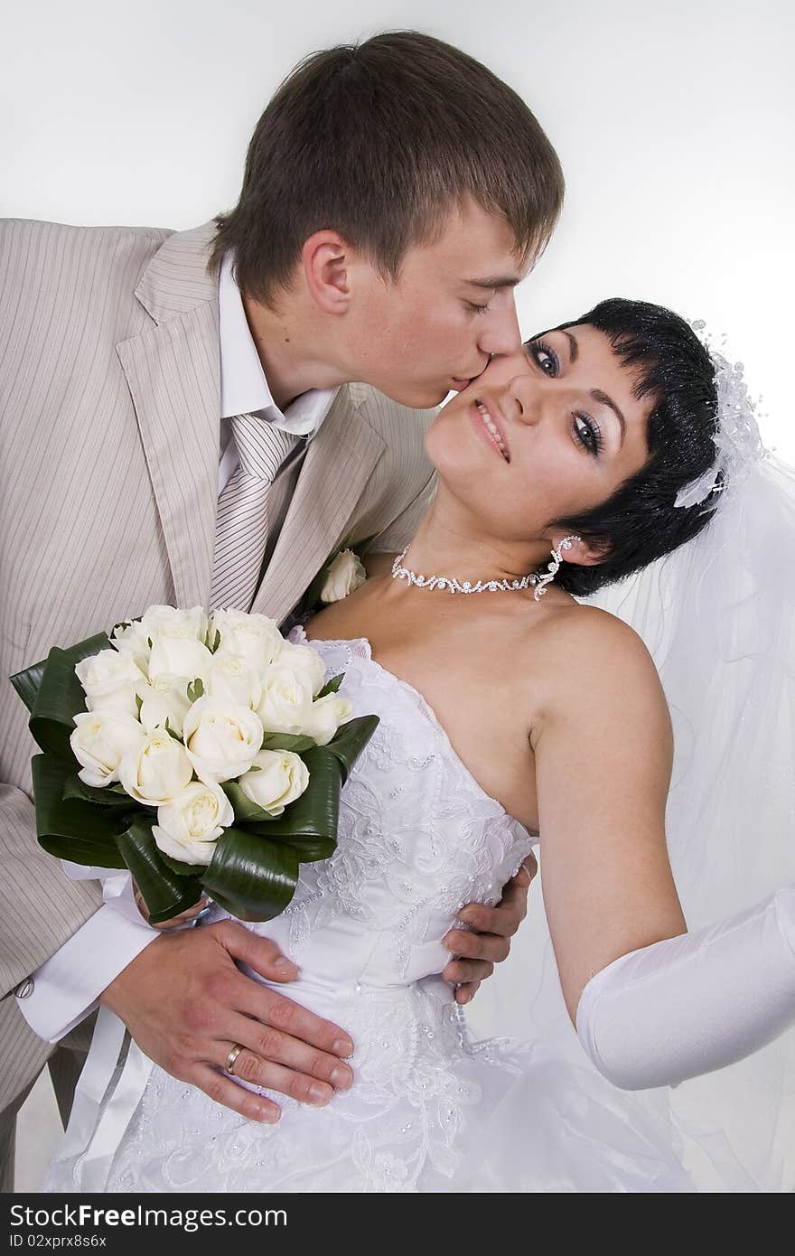 Loving groom and beautiful bride are happy together. A white background.