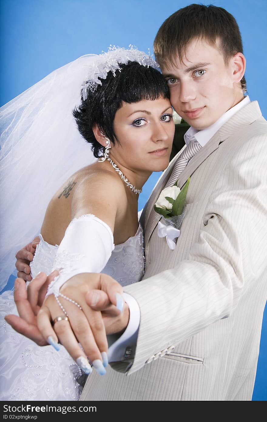 Loving groom and beautiful bride are happy together. Blue background.