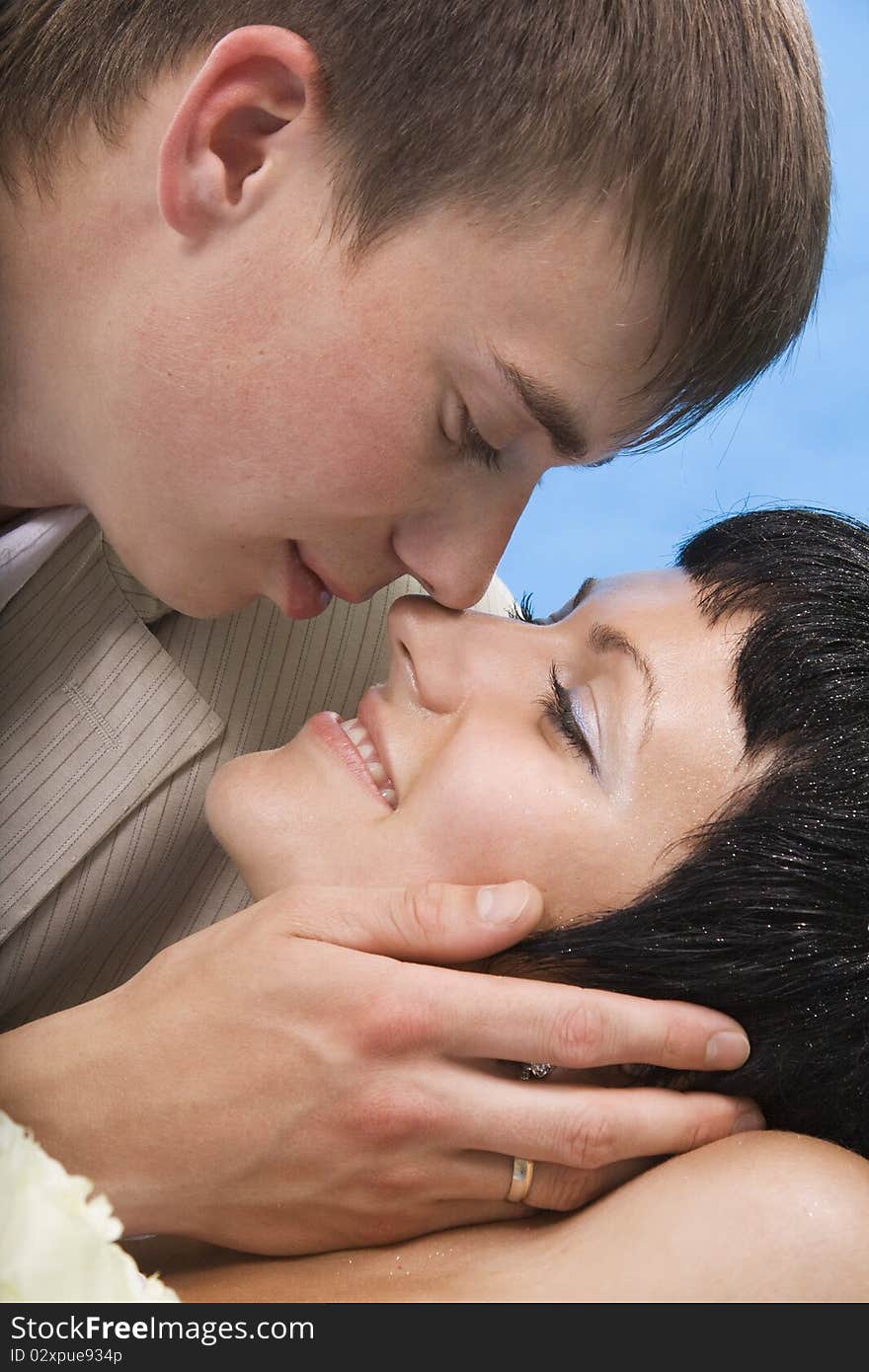 Loving groom and beautiful bride are happy together. Blue background.