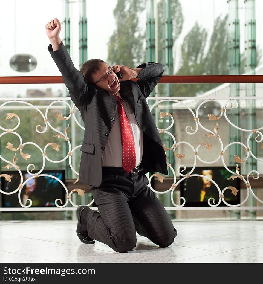 Smiling man with mobile phone on background of glass wall