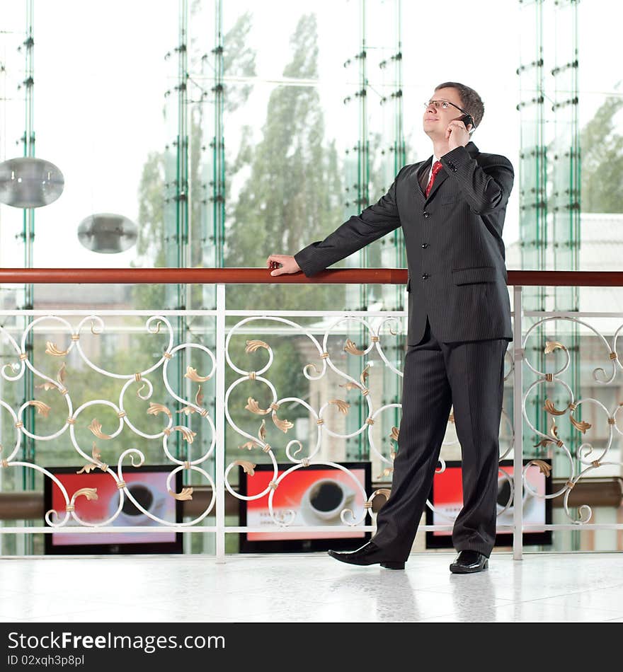 Smiling man with mobile phone on background of glass wall