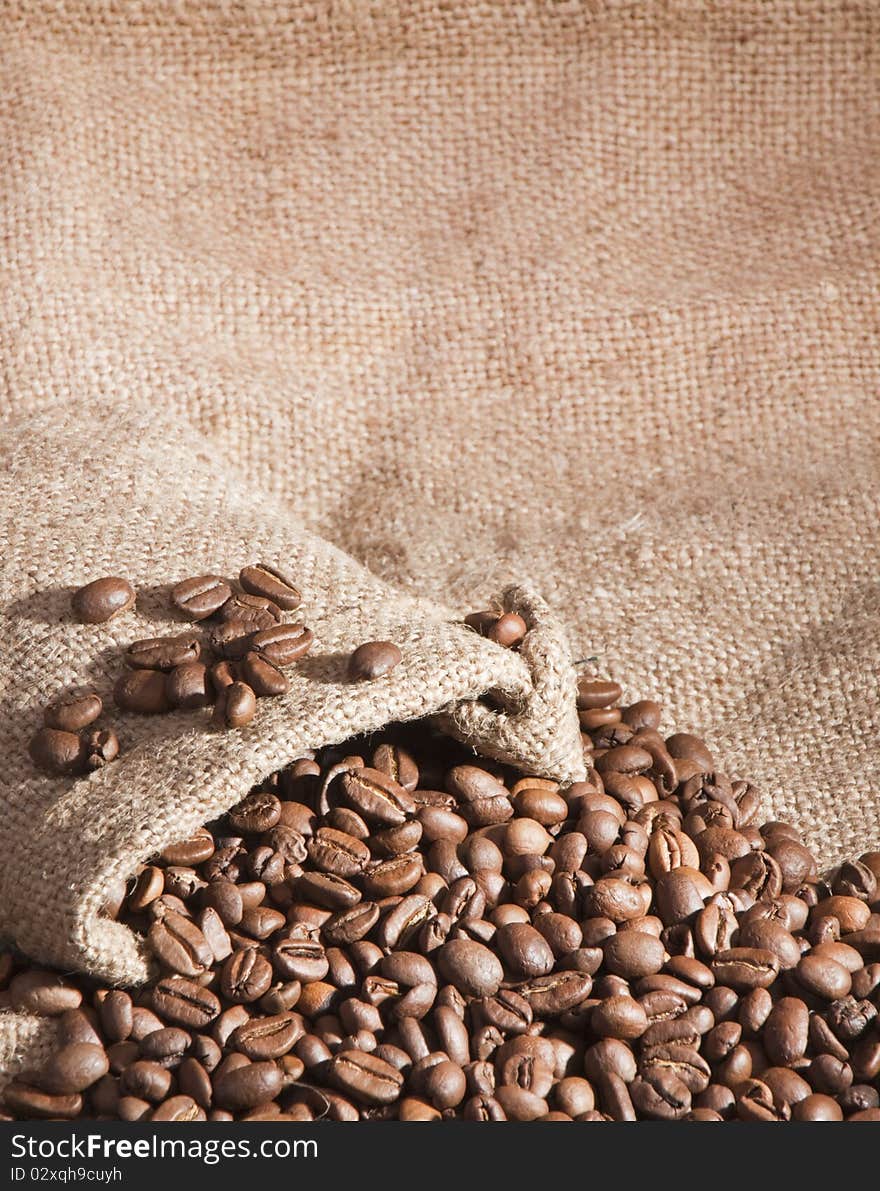 Spillage from the bag of coffee on burlap background