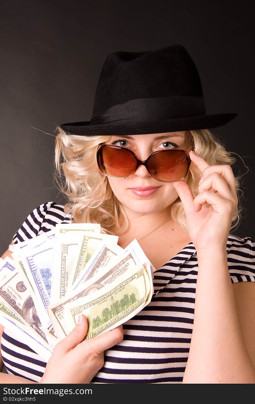 Photo of beautiful young woman of blonde in sunglasses and hat with money in a hand