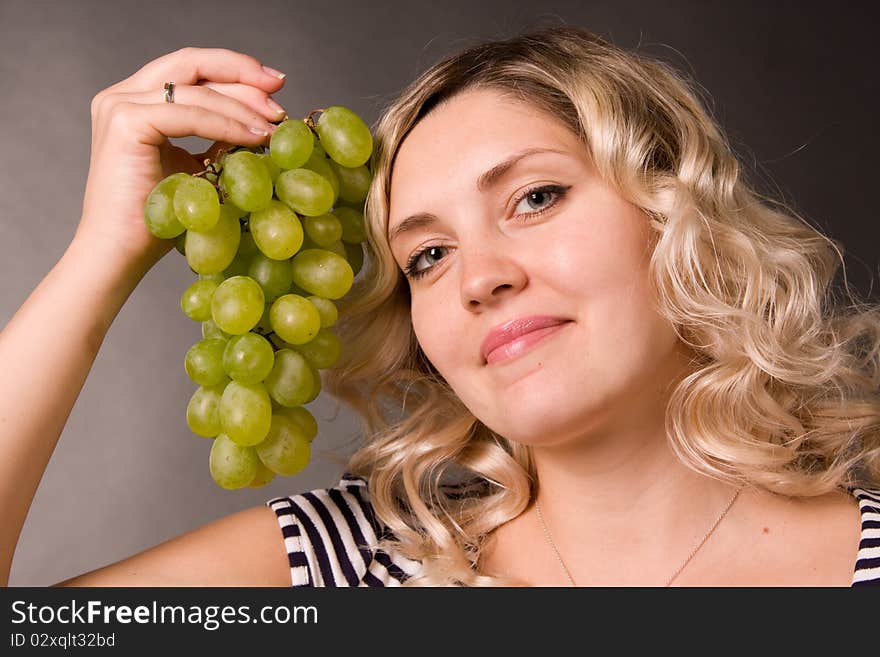 Beautiful young woman with the cluster of vine in a hand