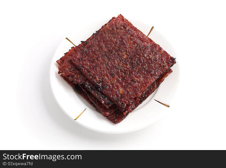 Close up of barbecue meat stacked on white plate isolated over white background.