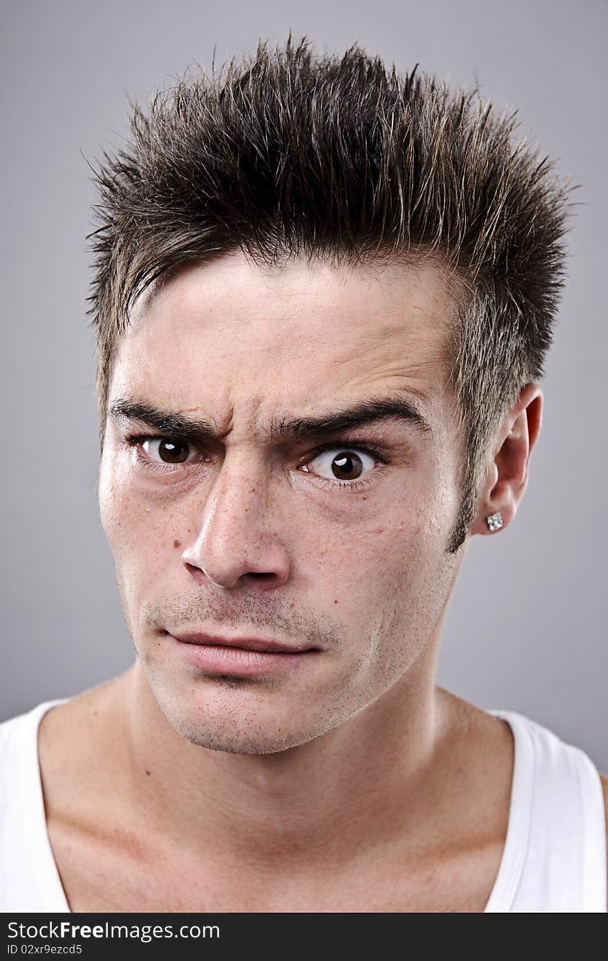 Man with spiky hair raises one eyebrow for portrait. Man with spiky hair raises one eyebrow for portrait