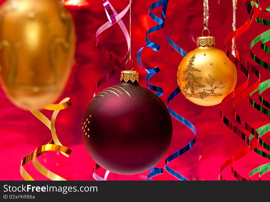 Red christmas ball and colored ribbons. Red background. Red christmas ball and colored ribbons. Red background