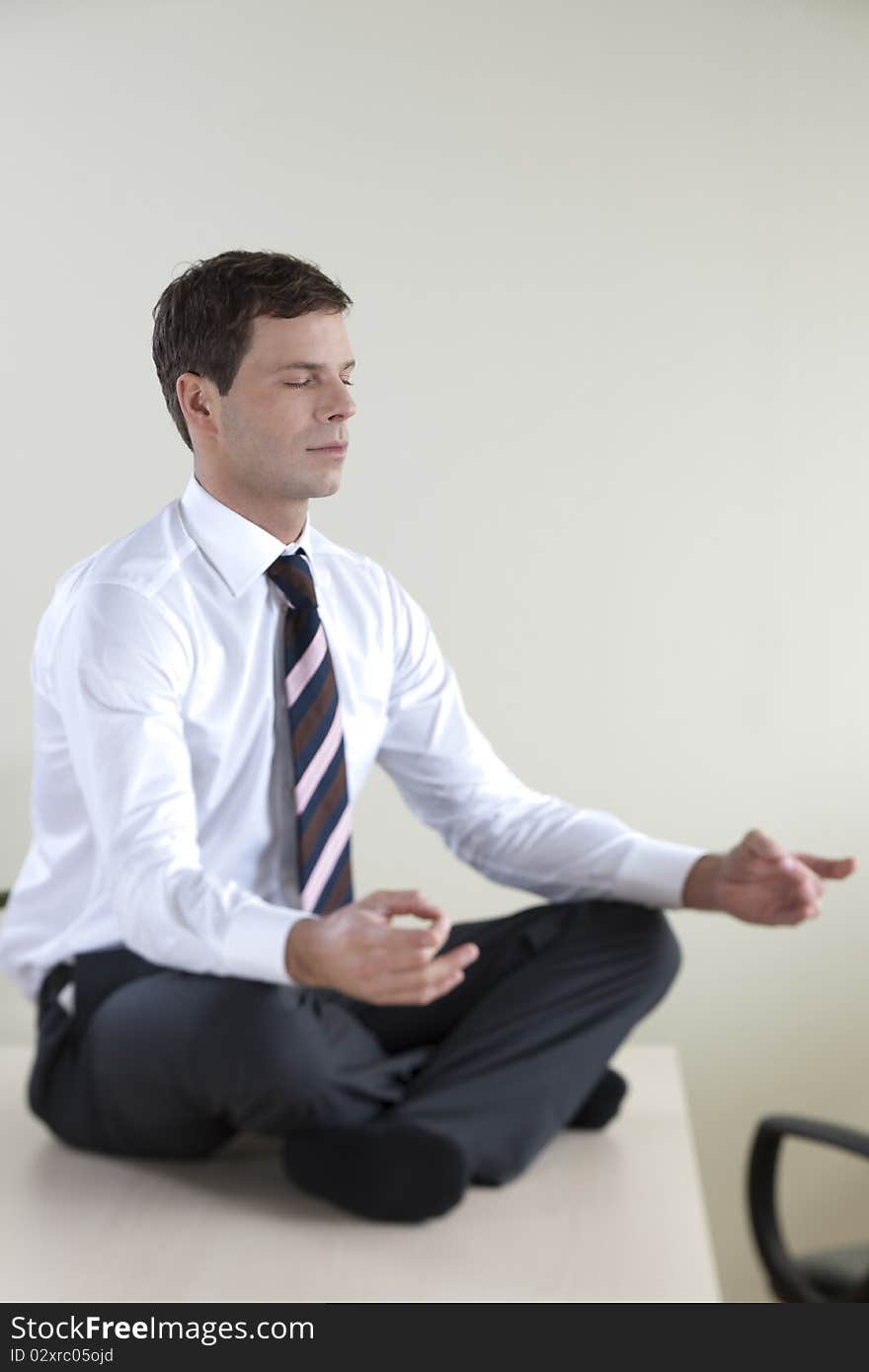 Young businessman meditating on his desk. Young businessman meditating on his desk