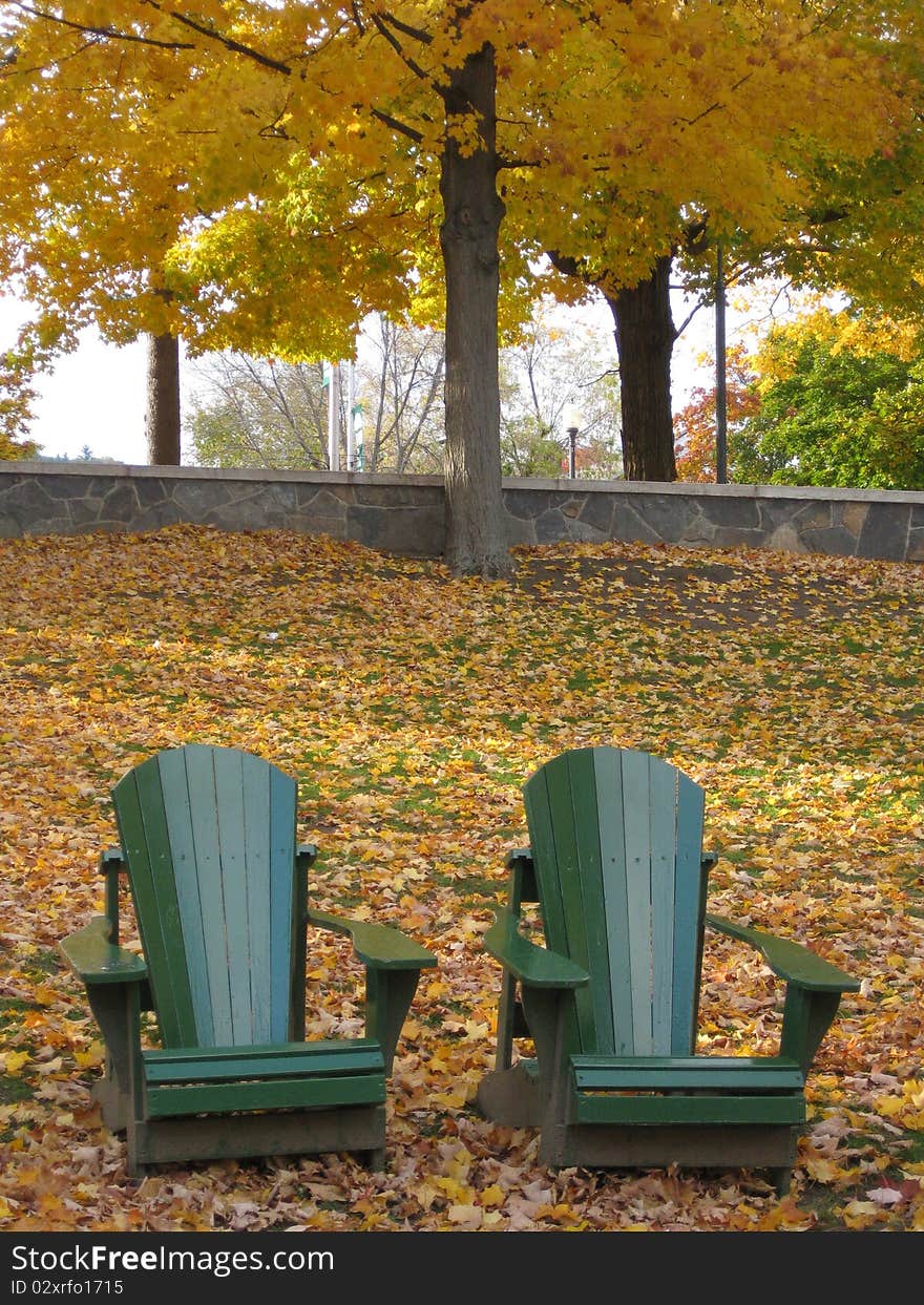 Two chairs sit amongst the fallen leaves giving a welcome to enjoy the foliage. Two chairs sit amongst the fallen leaves giving a welcome to enjoy the foliage.