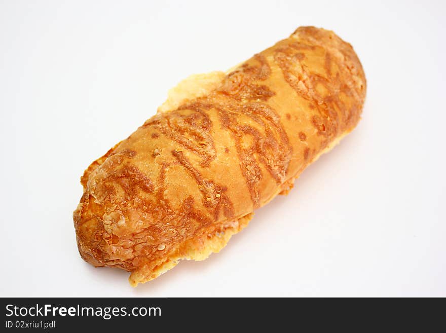 The ruddy long loaf of bread is strewed by cheese isolated on a white background