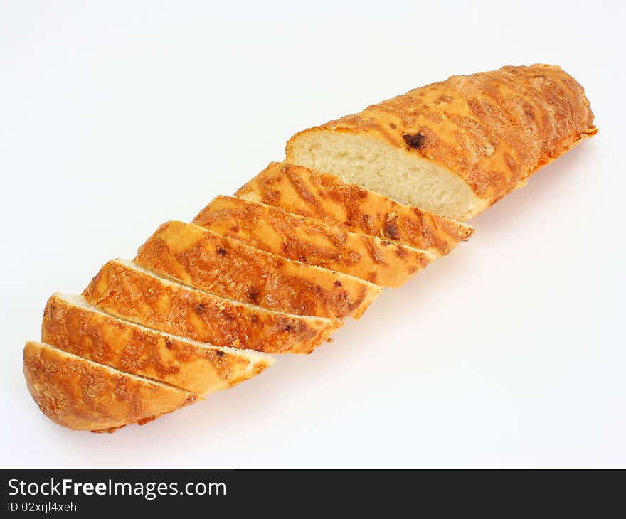 The ruddy long loaf of bread is strewed by cheese isolated on a white background