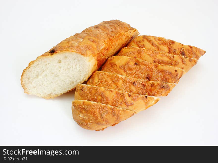 The ruddy long loaf of bread is strewed by cheese isolated on a white background