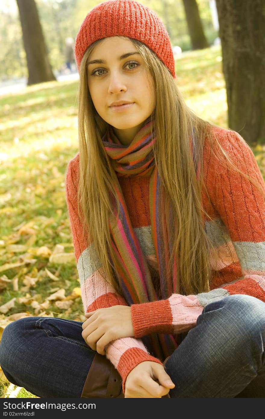 Portrait of a beautiful young woman. Sitting outside in a pile of autumn leaves, smiling. Portrait of a beautiful young woman. Sitting outside in a pile of autumn leaves, smiling