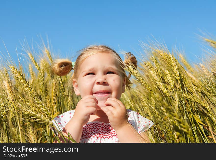 Happy cute toddler girl among ripe wheat ears. Happy cute toddler girl among ripe wheat ears