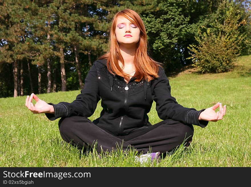 Young and beautiful red-haired girl meditating in nature