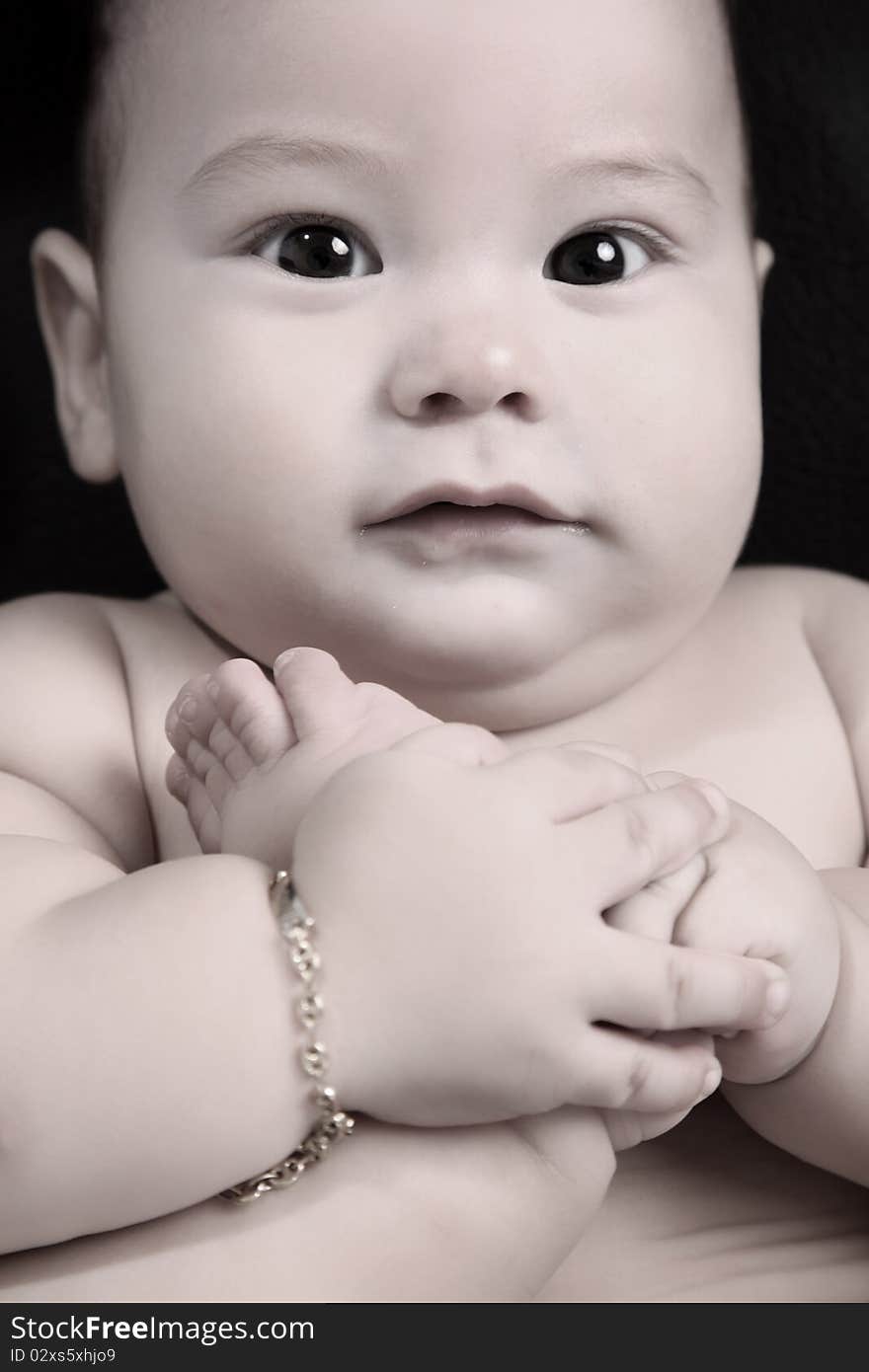 Baby taking his feet looking at the camera, head and body close up. Baby taking his feet looking at the camera, head and body close up