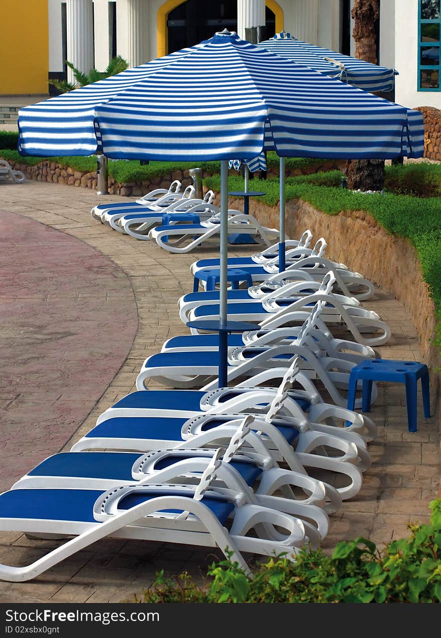 Sun chairs and umbrellas near hotel swimming pool