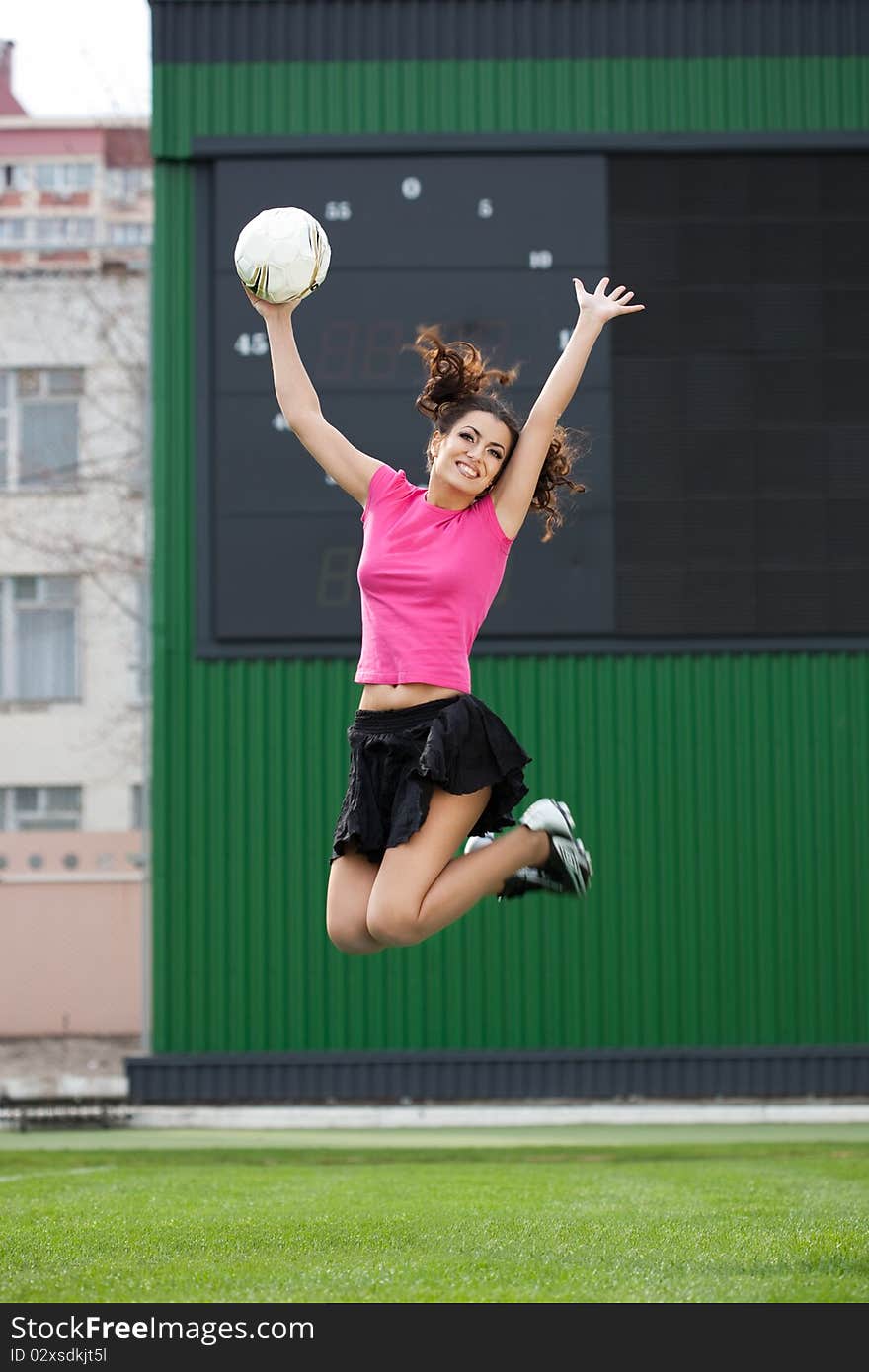 Girl cheerleaders jumping with a soccer ball