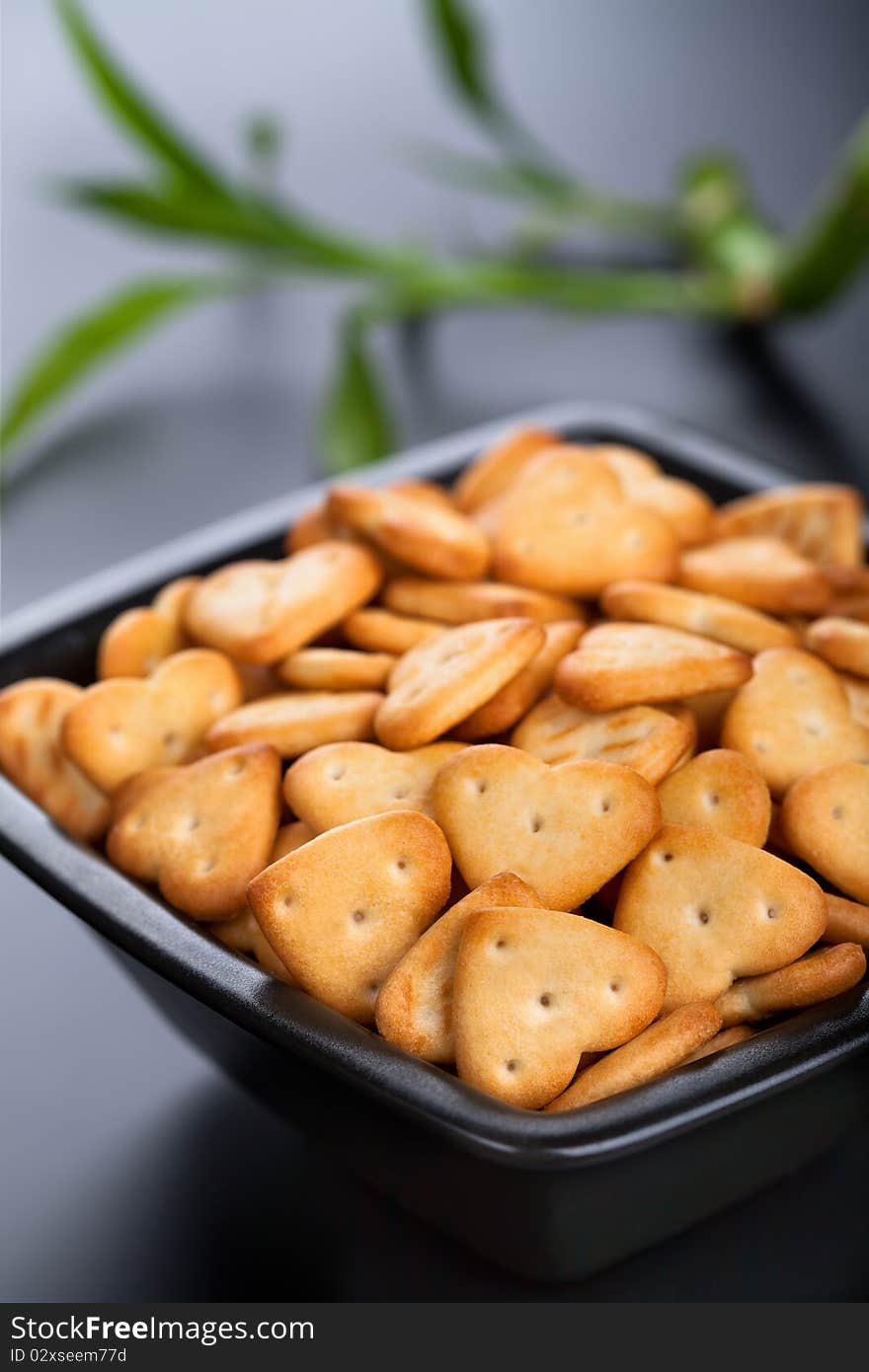 Salted heart shaped crackers in black bowl. Salted heart shaped crackers in black bowl