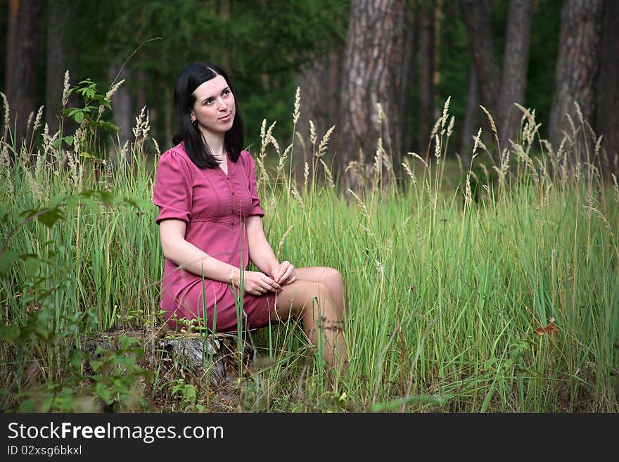 Girl in a red dress sitting on a stump in the woods. Girl in a red dress sitting on a stump in the woods