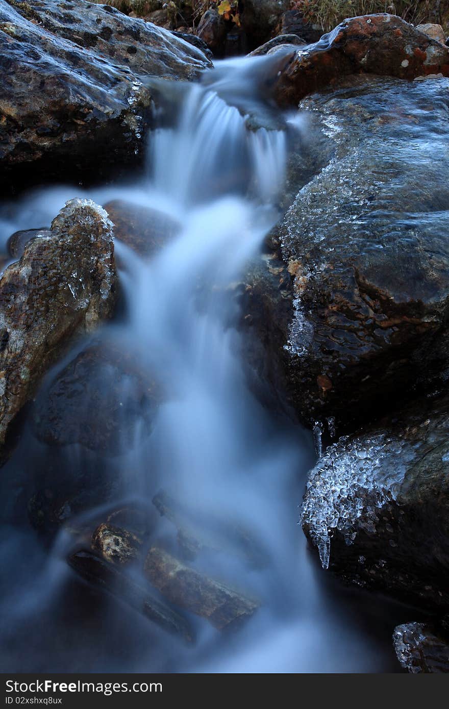 Mountain stream in cold weather and with ice on the rocks