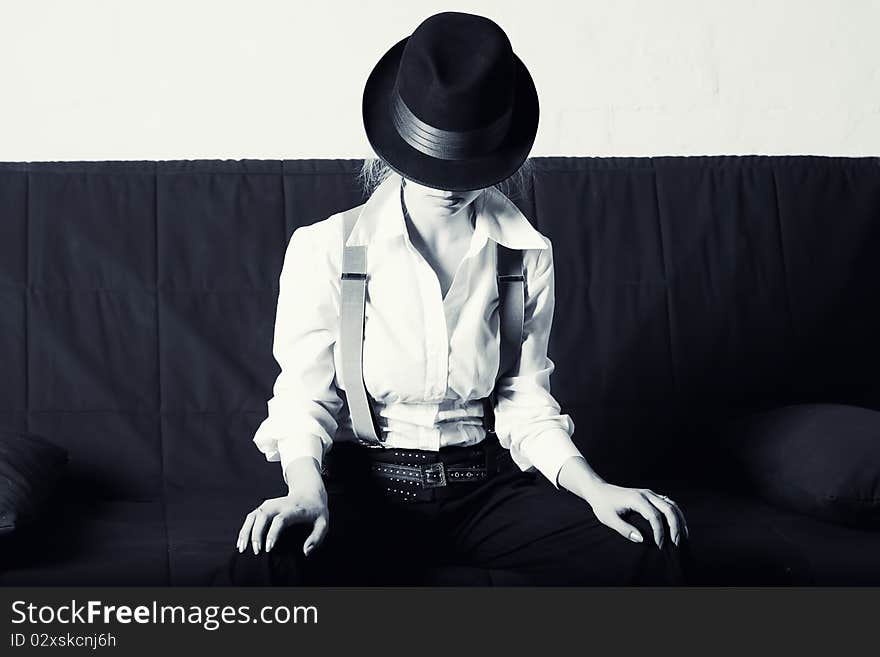 Woman in classic men's hat, and a shirt sitting on the sofa