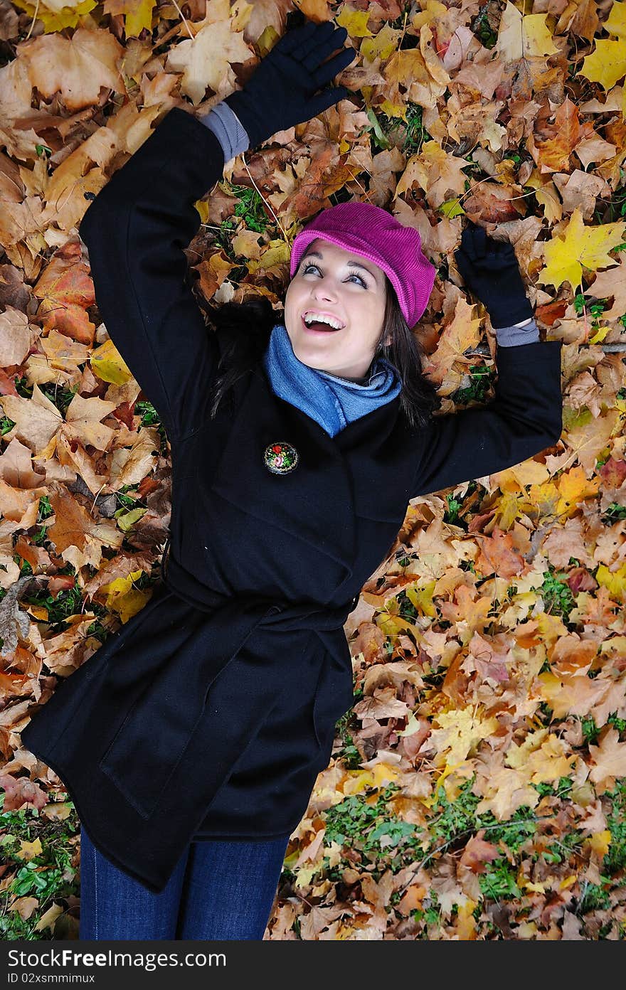 Pretty autumn girl relaxing outdoors in the forest on the fallen leafs