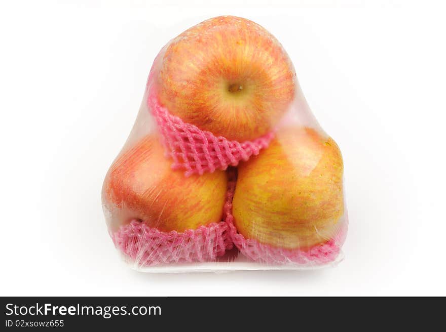 Close up of three apple shipping net on a white surface.