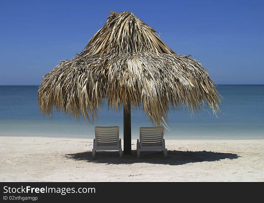 Two chairs and palapa in front of the ocean. Two chairs and palapa in front of the ocean