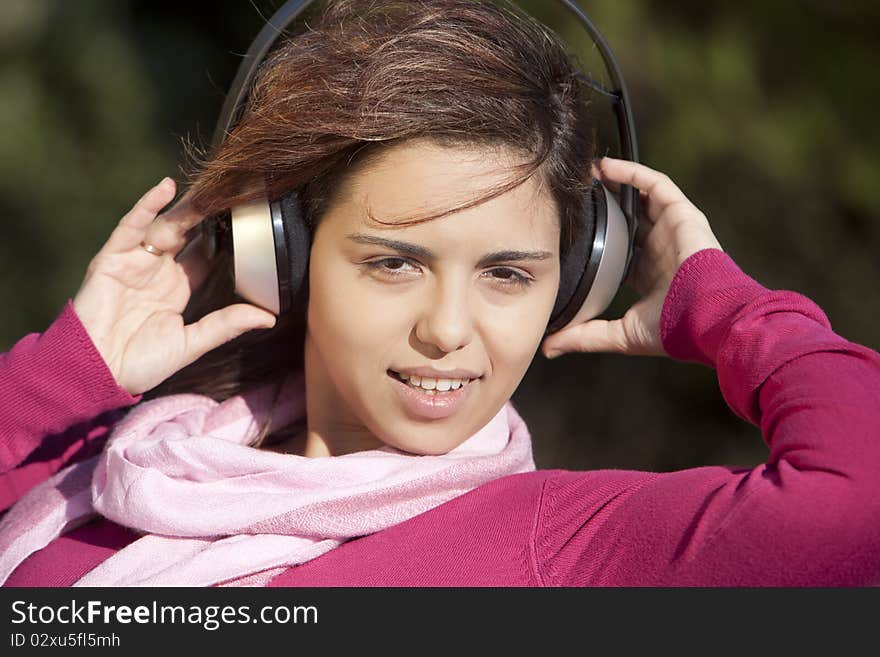 Pretty young girl listening music in the park