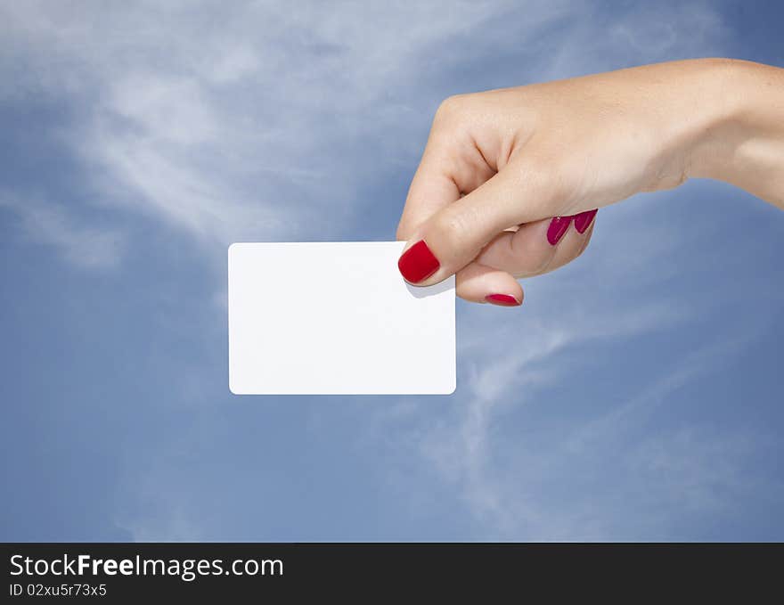 Hand holding an empty business card with a blue sky background