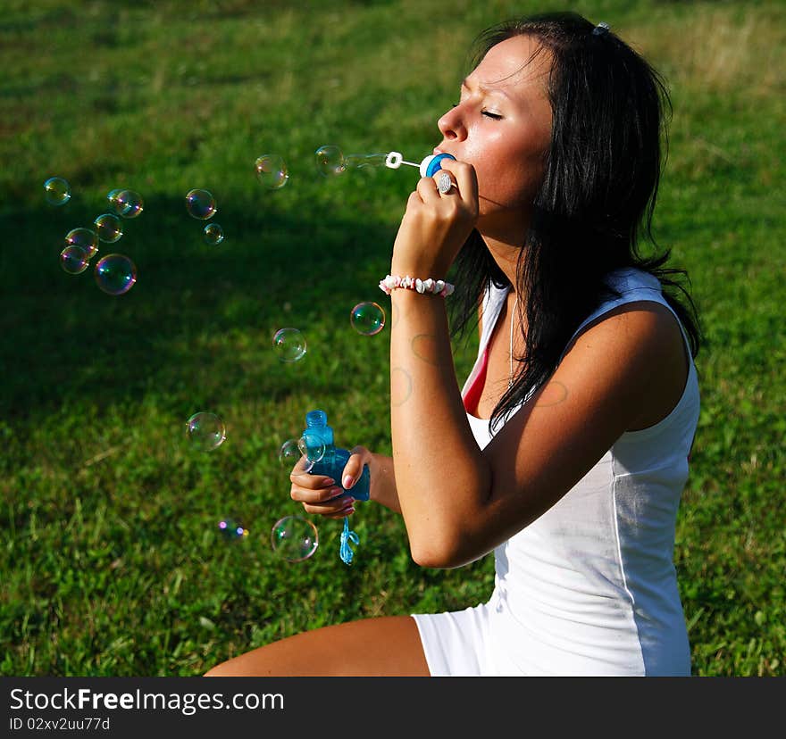 Young beautiful girl blowing bubbles in the nature