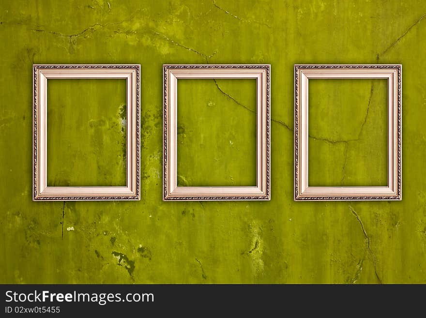 Three blank frames hanging on vintage green cracked wall