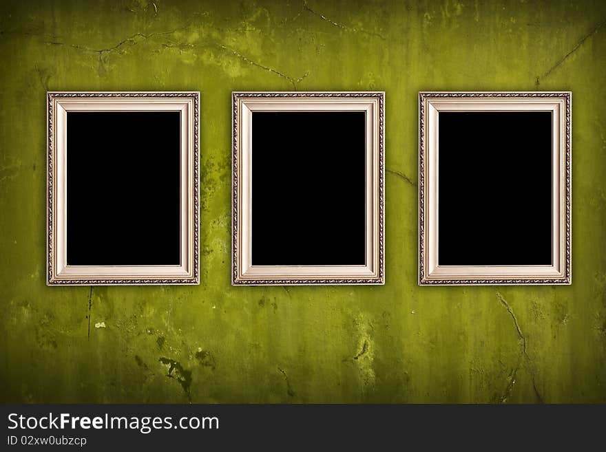 Three blank frames hanging on vintage green cracked wall