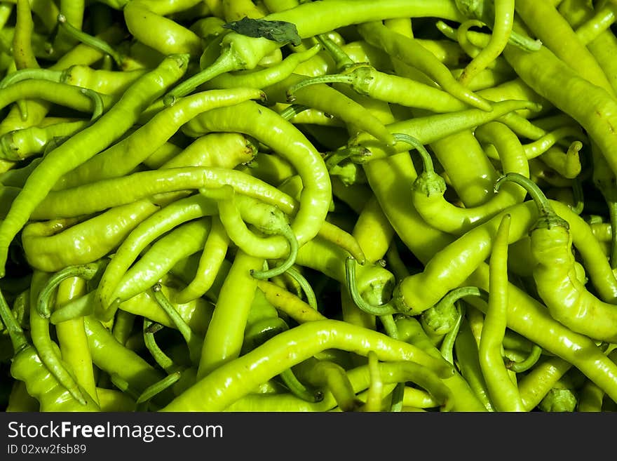 Pile of green pepperoni at the local market.