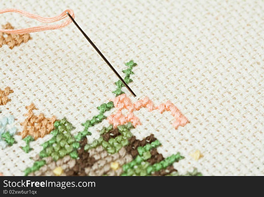 Closeup of needle put into cross-stitch embroidery.