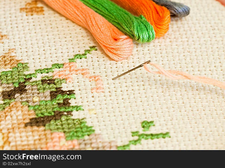 Closeup of needle put into cross-stitch embroidery.