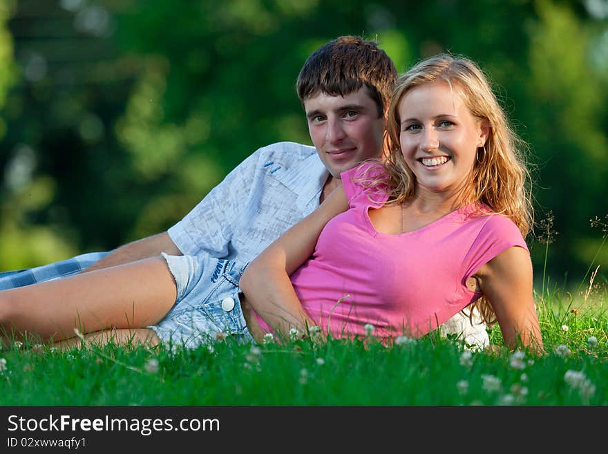 A couple relaxing in the park, lying on the grass, lit in the evening sun