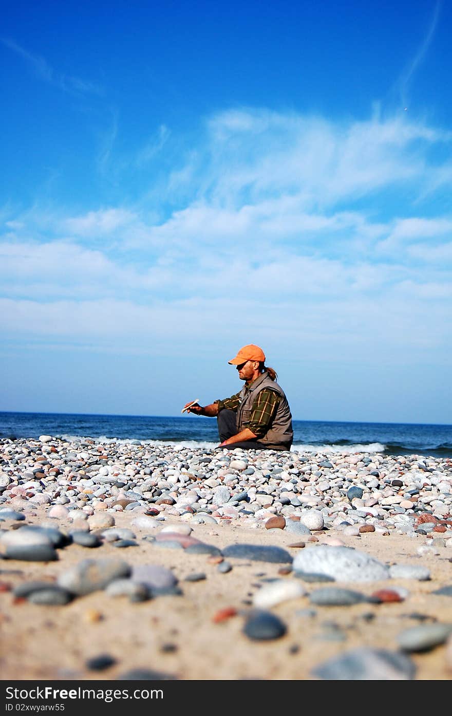 A man sitting on a rocky beach in early autumn.