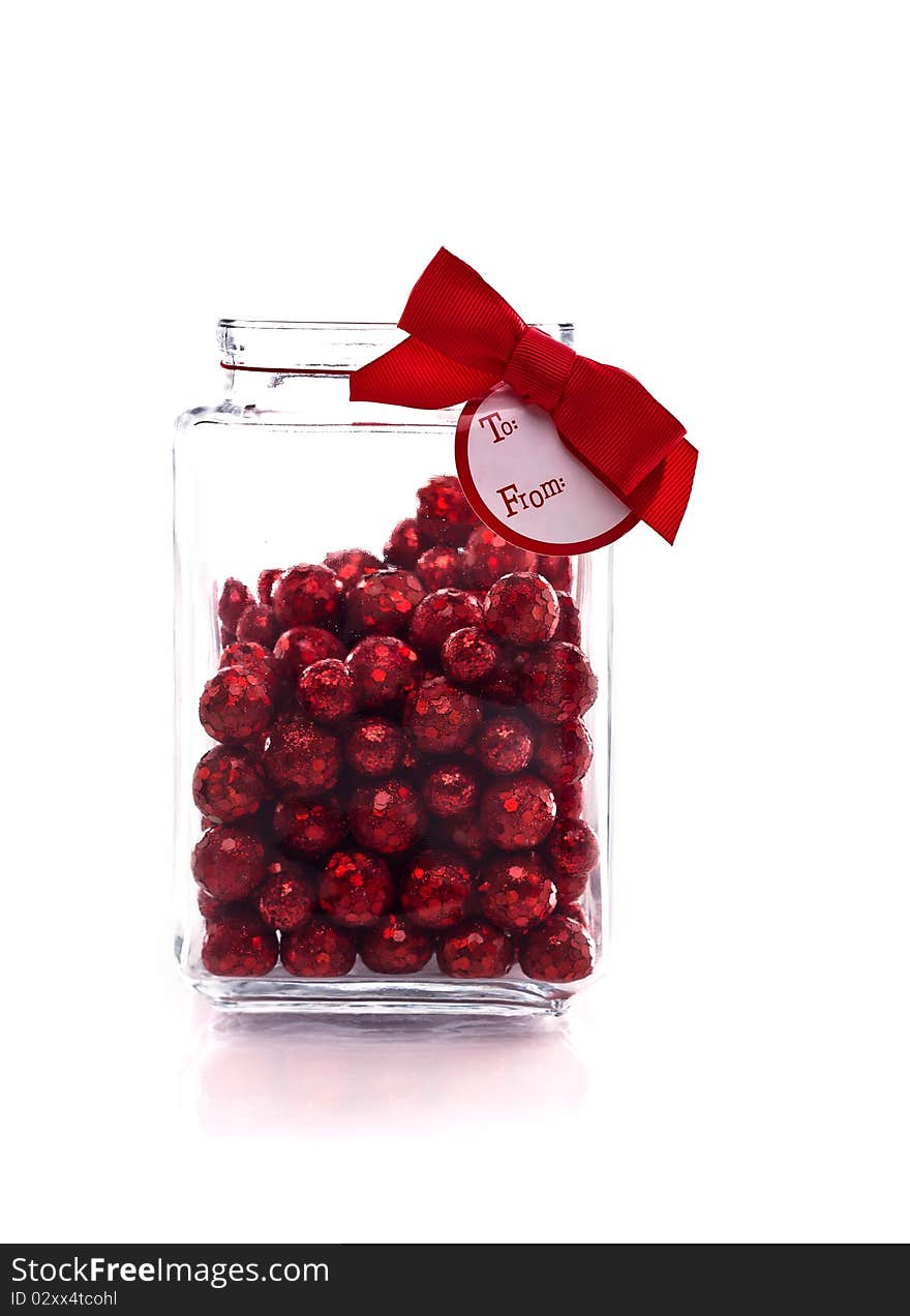 Candy jar with red glittery candy, and gift tag isolated on white with copy space