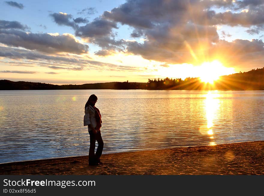 A beatiful girl was walking on the beach in the sunset. The lake of Two Rivers is a quite famous lake in Algonquin, Ontario, Canada. A beatiful girl was walking on the beach in the sunset. The lake of Two Rivers is a quite famous lake in Algonquin, Ontario, Canada