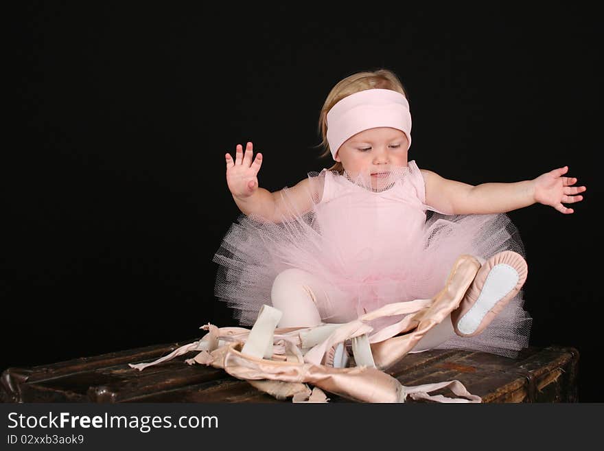 Baby ballerina sitting on an antique trunk